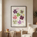 Lámina ilustrada de tréboles de Oxalis enmarcada en negro sobre una mesa junto a un sillón y plantas
